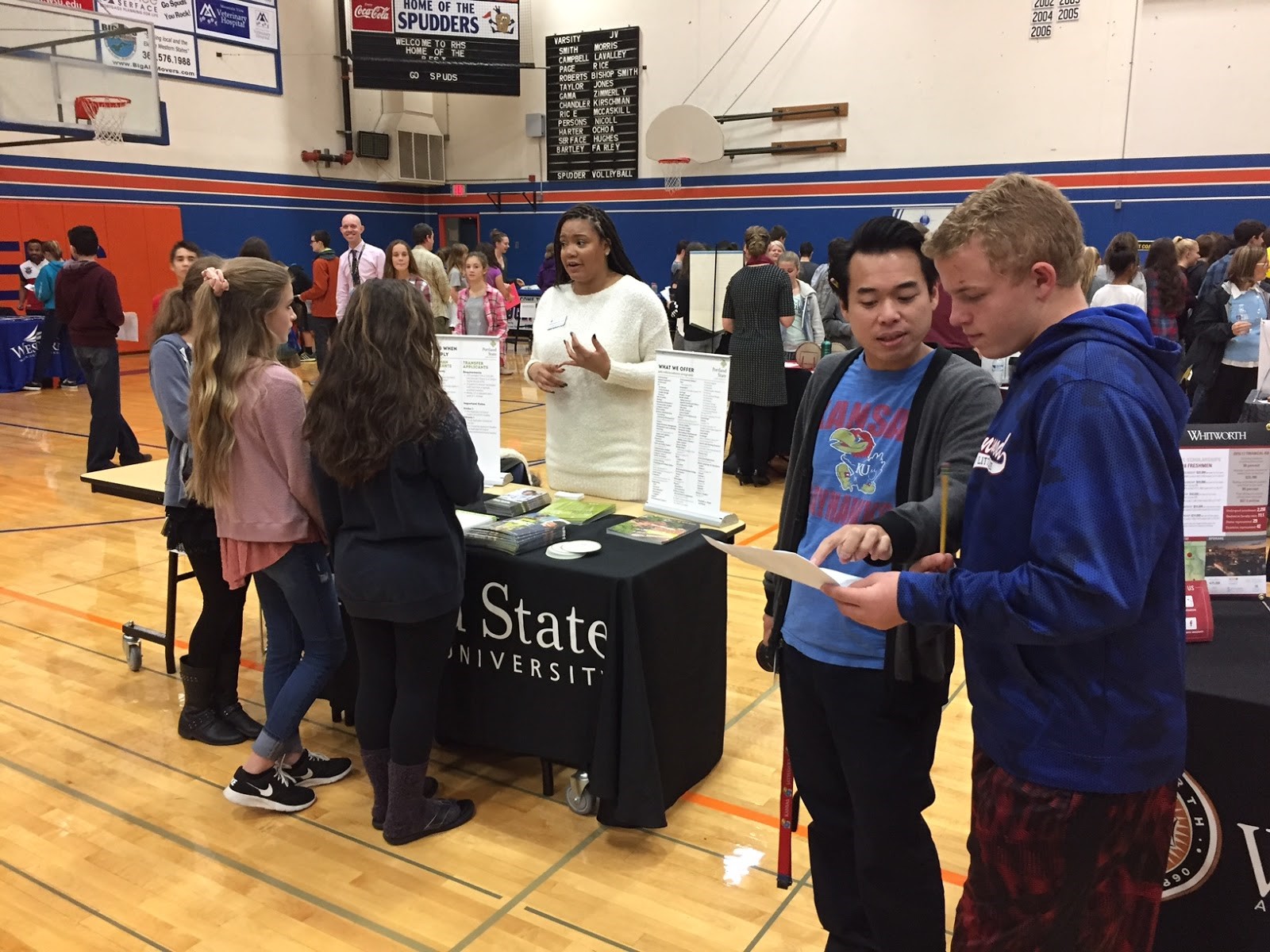 View Ridge Middle School student, Elijah Engstrom, consults with teacher, Nam Nguyen at the Fall College Fair.  In the background, students get information about Portland State University.